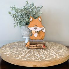 a small wooden fox sitting on top of a table next to a vase with flowers