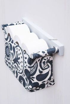 a black and white bag hanging on the side of a wall with two rolls of toilet paper in it