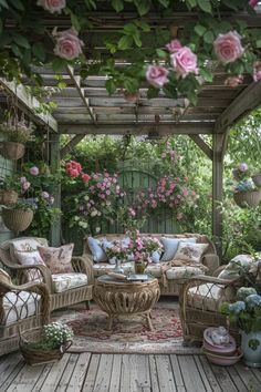 an outdoor living area with wicker furniture and pink flowers on the arbor, surrounded by greenery