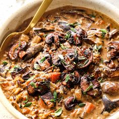 a close up of a bowl of soup with mushrooms and carrots in it on a table