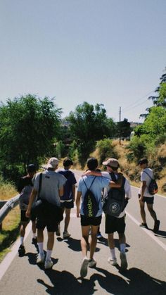 a group of people walking down the road with backpacks on their backs and back