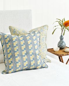 pillows and vases on a bed with white sheets