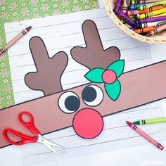 the paper reindeer is next to some crayons and colored pencils in front of it