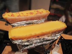 two hot dogs covered in cheese sitting on top of foil