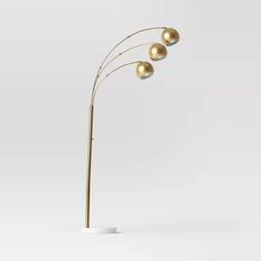 three golden balls are on the top of this floor lamp, and it's light shines brightly