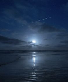 the moon shines brightly in the night sky over the ocean on a cloudy day