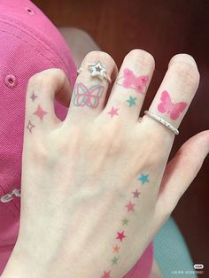 a woman's hand with pink and blue stars on it, holding up her ring