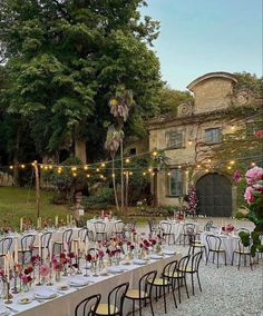 an outdoor dining area with tables and chairs set up for a formal dinner in the garden