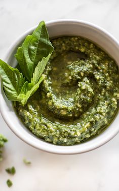 a white bowl filled with pesto and topped with green leafy garnish