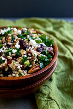 a wooden bowl filled with nuts and greens