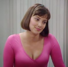 a woman in a pink shirt is looking at the camera