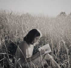 a woman sitting in the grass reading a book