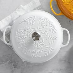 a white casserole dish sitting on top of a counter next to a yellow pot