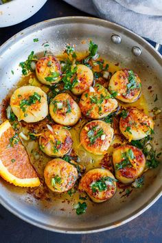 a pan filled with cooked scallops and orange slices