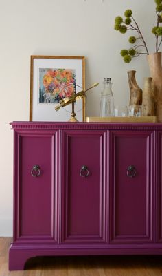 a purple cabinet with three doors and vases on top