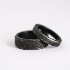 two wedding rings sitting next to each other on top of a white surface with no background