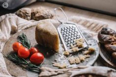 bread, tomatoes and other foods are on a plate with a grater next to them