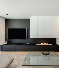 a modern living room with fireplace and flat screen tv on the wall, along with white cabinets