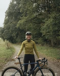 a woman standing next to a bike on a dirt road