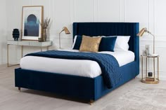 a bed with blue velvet headboard and white bedspread in a bedroom setting