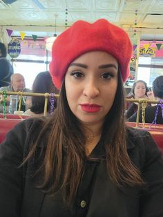 a woman wearing a red hat sitting in a booth at a restaurant with other people