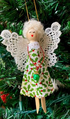 an angel ornament hanging from a christmas tree with green and red ornaments on it