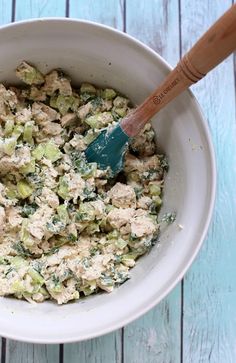 a bowl filled with chicken and broccoli on top of a blue wooden table