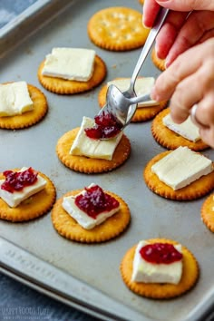 crackers with cream cheese and jam being spread on them