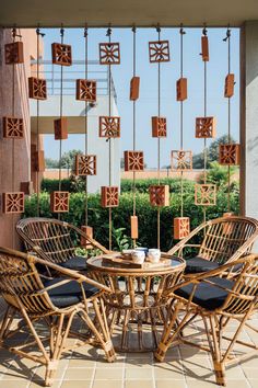 an outdoor table and chairs with wooden decorations hanging from the ceiling above them, on a tiled patio