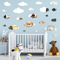 a baby's room with a crib, stuffed animals and clouds on the wall