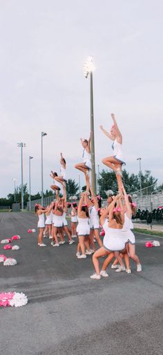 a group of cheerleaders are doing tricks in the air on a street light pole