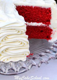 a slice of red velvet cake with white frosting on a glass plate next to the rest of the cake