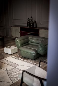 a green leather couch sitting on top of a wooden floor next to a white rug