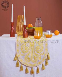 a table topped with oranges and juice on top of a white table cloth covered table