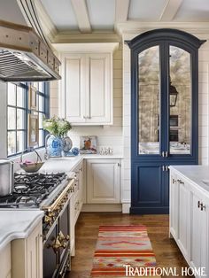 a kitchen with white cabinets and blue trim on the door, along with an area rug