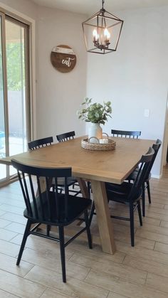 a dining room table with black chairs and a potted plant on top of it