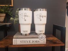 two white tumblers sitting on top of a stack of books