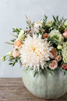 a vase filled with lots of flowers on top of a wooden table