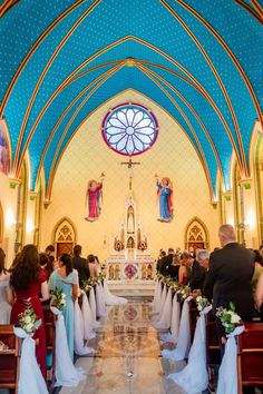 a wedding ceremony in the church with people sitting at the pews and looking on