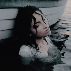 a woman laying in the water next to a boat