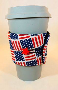 a coffee cup sleeve with an american flag design on the front and bottom, attached to a gray plastic cup