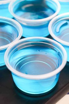 blue plastic cups sitting on top of a black tray filled with water and ice cream