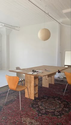 a large wooden table sitting in the middle of a room with chairs and a rug