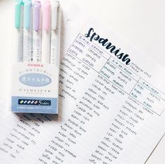 three pens sitting on top of a paper next to some writing practice sheets and pencils