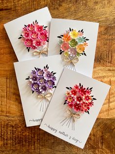 four greeting cards with flowers on them sitting on a table next to a wooden surface