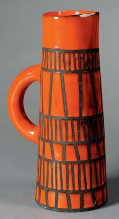 an orange and black ceramic mug on a gray surface with lines drawn across the top