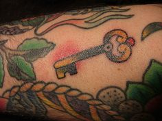 a close up of a person's arm with a tattoo on it and a key