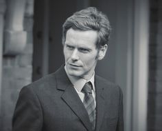 a black and white photo of a man in a suit looking off to the side