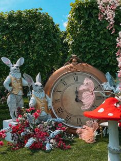 a clock with rabbits and flowers around it on the grass in front of some trees