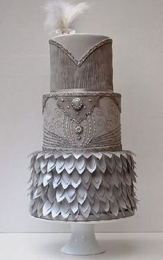 a three tiered cake with feathers on top